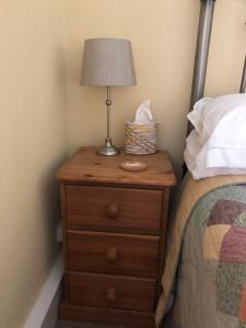 a nightstand with a lamp on it next to a bed at The Stoep in Paignton