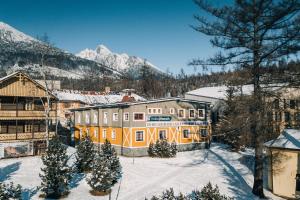 a building in the snow with trees and mountains at APLEND Koliba Kamzík in Vysoke Tatry - Stary Smokovec
