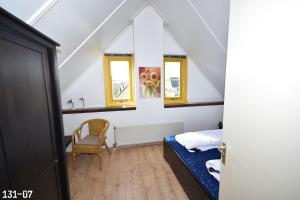 1 dormitorio con 1 cama, 1 silla y ventanas en Strandparel 5 personen en Julianadorp