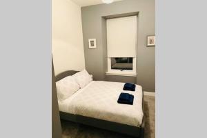 a small bedroom with a bed with a window at Bellshill central apartments in Bellshill