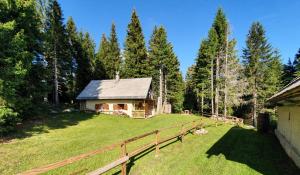 a house in the middle of a yard with a fence at MOUNTAIN ECO CHALET KONJSKA DOLINA on 1400 m asl -near Pokljuka in Srednja Vas v Bohinju