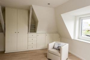een witte kamer met een stoel en een raam bij Meeresbriese-Landhaus-Tadsen in Westerland
