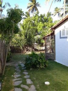 un cortile sul retro di una casa con un giardino con erba e alberi di Chalé Gostosomar a São Miguel do Gostoso