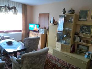 ein Wohnzimmer mit einem Tisch, Stühlen und einem TV in der Unterkunft Ferienwohnung Gohlke in Kamschlacken
