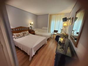 Cette chambre comprend 2 lits et un miroir. dans l'établissement Arha Villa de Suances - Antiguo Albatros, à Suances