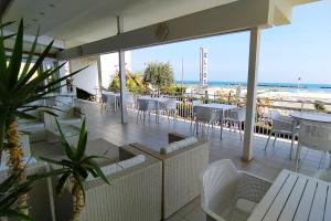 un patio con sillas y mesas blancas y la playa en Hotel Elios, en Bellaria-Igea Marina