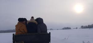 grupa ludzi siedzących na ławce w śniegu w obiekcie Dom Piotra w mieście Goniadz