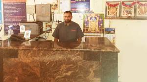 Un uomo in piedi dietro un bancone in una stanza di Vishnu Residency Warangal a Warangal