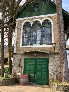 una casa con una puerta verde y un árbol en Güns Vendégház, en Szigliget