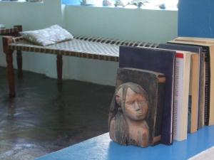 une statue d'une tête assise sur une table à côté des livres dans l'établissement Chiky Villa, à Watamu