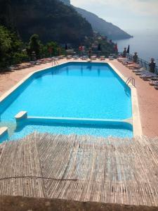 a large blue swimming pool with chairs and the ocean at Belview Positano in Positano