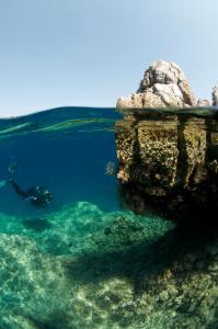 a person swimming in the water near a rock formation at Saronis Hotel in Ancient Epidavros