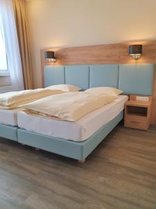 Schlafzimmer mit einem großen Bett mit einem Kopfteil aus Holz in der Unterkunft Nordseehotel Wilhelmshaven in Wilhelmshaven