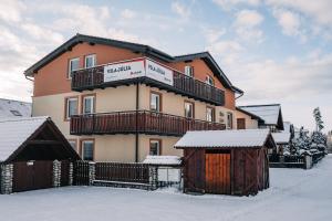 ein großes Gebäude mit Schnee auf dem Boden in der Unterkunft APLEND Vila Júlia in Tatranská Lomnica