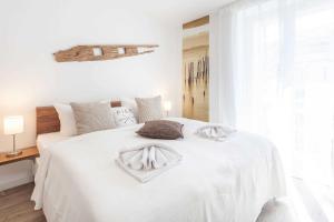 um quarto branco com uma cama com lençóis e almofadas brancos em Villa Strandidyll FeWo pier25 N 1 em Binz