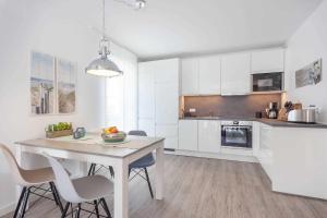 uma cozinha com armários brancos e uma mesa e cadeiras em Villa Strandidyll FeWo pier25 N 1 em Binz