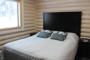 a bedroom with a bed with a black headboard and a window at Hiekkaranta Holiday Home in Parikkala