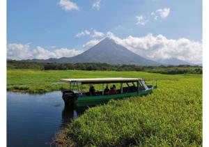 a boat on a river with a mountain in the background at Cabinas Los Tucanes Private Room #4 with Volcano view in Fortuna