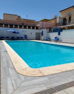 a swimming pool with blue water in front of a building at Coral sea in San Vito lo Capo +14 photos