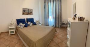 a bedroom with a large bed with blue pillows at Coral sea in San Vito lo Capo