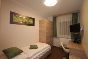 Habitación de hotel con cama, escritorio y TV. en Pension Central Semmering, en Semmering