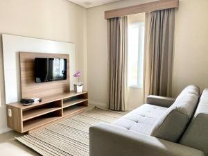 a living room with a couch and a flat screen tv at Apartamento em Holambra in Holambra