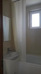 baño blanco con lavabo y ventana en Irvin Apartament en Iaşi