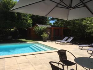 uma piscina com cadeiras, uma mesa e um guarda-sol em la Grange de Félicie em Charrey-sur-Saône