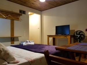 a bedroom with a bed and a tv and a table at Pousada Verde & Rio Lumiar in Lumiar