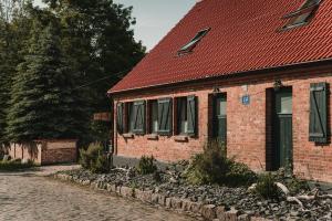 a brick house with a red roof on a street at Osada pod Lipą in Ostrowice