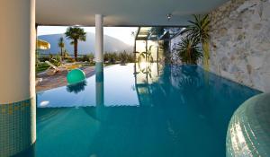 a swimming pool in a house with a blue pool at Hotel Appartements Graf Hartwig in Schenna