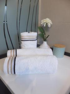 three towels on a table with a vase with a flower at Les gîtes de "La Quesnoyère" in Quesnoy-le-Montant +24 photos