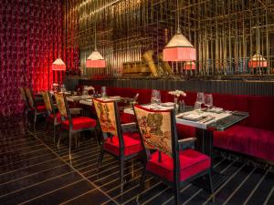 a dining room with tables and chairs and red curtains at Capella Hanoi in Hanoi