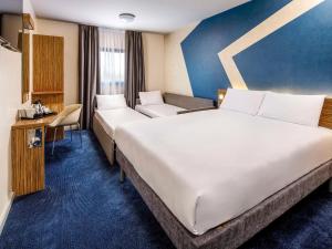 a hotel room with a large white bed and a chair at ibis budget London Heathrow Terminal 5 in Slough