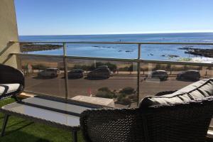 uma varanda com vista para um parque de estacionamento e para o oceano em Magnifique duplex super cosy Vue mer 180 em Ploemeur