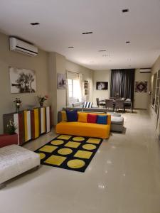 ein Wohnzimmer mit einem gelben Sofa und einem Teppich in der Unterkunft Cavalli apartments in Madinat as-Sadis min Uktubar