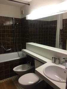 ein Badezimmer mit einem WC, einem Waschbecken und einem Spiegel in der Unterkunft Disentiserhof C502 in Disentis