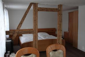1 dormitorio con 1 cama de madera con dosel y 2 sillas en Ferienwohnung Lippmann, en Großhartmannsdorf