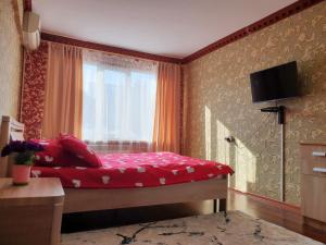 Un dormitorio con una cama con sábanas rojas y una ventana en Уютная Однушка en Atyraū