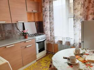 eine kleine Küche mit einem Tisch und einem Herd in der Unterkunft Уютная Однушка in Atyrau