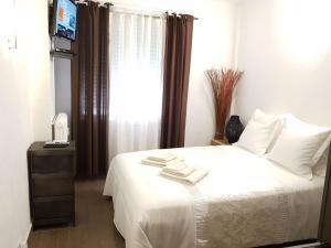 a bedroom with a bed with white sheets and a window at Les Pieds dans l'Eau in Nice