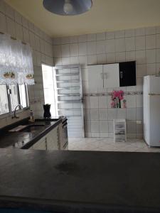 a kitchen with a black counter top and a white refrigerator at Casa grande e confortável em Ilha Comprida in Ilha Comprida +11 photos