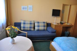 a living room with a blue couch and a table at Pension Müritzblick in Waren