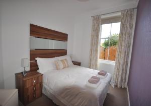 1 dormitorio con cama blanca y ventana en Links Corner, en Gullane