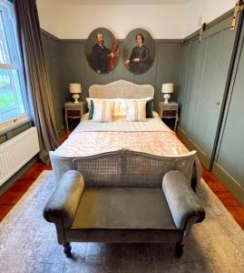 a bedroom with a large bed with two portraits on the wall at The Crown Inn Dial Post in Horsham