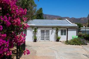 a white house with pink flowers in front of it at Die Dorpshuis in Calitzdorp