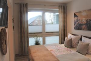 een slaapkamer met een bed en een groot raam bij Apartment am See, Am Alten Deich 4-6, Whg 1 24 in Dangast