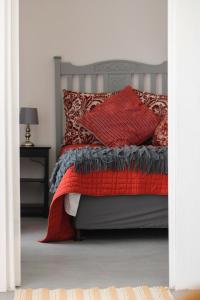 a bedroom with a bed with red pillows at Die Dorpshuis in Calitzdorp