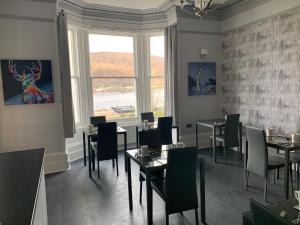 a dining room with tables and chairs and a window at Ashburn House in Fort William