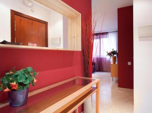 a room with a red wall with a bench and a potted plant at PORTAL DEL ANGEL Barcelonastuff Apartments in Barcelona